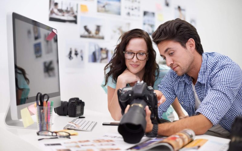 two-young-photographers-looking-at-photos-on-a-digital-camera-in-their-studio-1.jpg